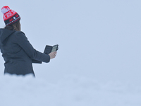 A woman takes a picture with her mobile phone near the Krakus Mound covered with snow in Krakow, Poland, on January 21, 2023.
Since Thursday...