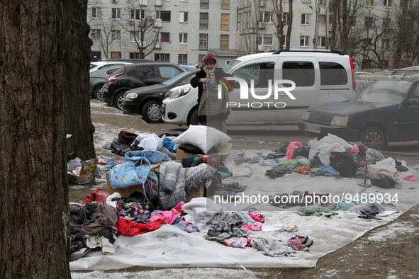 DNIPRO, UKRAINE - JANUARY 23, 2023 - A woman holds a jacket as clothes brought by people are arranged on the ground near the residential bui...