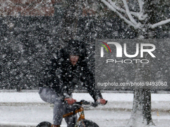 A man rides a bicycle on the snow covered sidewalk amid heavy snow fall at Norman, Oklahoma, USA. 24 January 2023. (