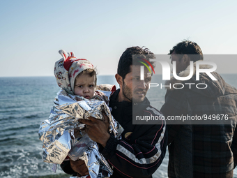 A man holds her child on a beach near to the town of Mytilene after crossing a part of the Aegean sea on a dinghy, with other refugees and m...