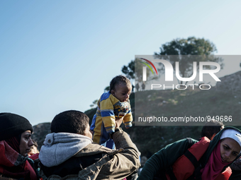 Brother holds up a baby as others help migrants and refugees to disembark from a dinghy after their arrival from the Turkish coast to the Gr...