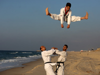 Palestinian youths show their skills and practice taekwondo on the Mediterranean beach during sunset in Khan Yunis, southern Gaza Strip. The...