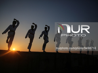 Palestinian youths show their skills and practice taekwondo on the Mediterranean beach during sunset in Khan Yunis, southern Gaza Strip. The...