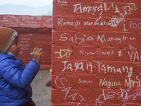 A child writes a message on a wall at the Saraswati temple on the occasion of the Hindu festival of Sawaswati Puja or Shree Panchami, in Kat...