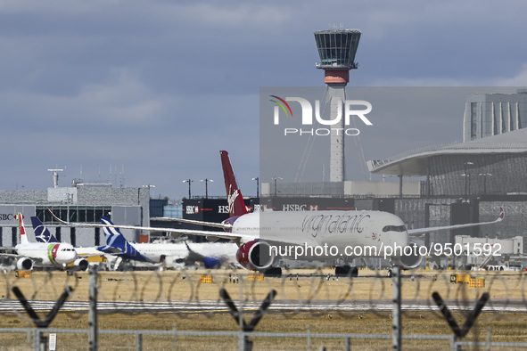 Virgin Atlantic Airways Airbus A350-1000 aircraft as seen taxiing infront of other planes, the air traffic control tower, the gates of the t...