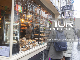 People outside of a bakery - pastry shop look the display. Snow in Maastricht with cold weather. Daily life and general view scenes of the r...