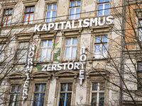 The facade of the occupied housing project Kastanienallee 86 with a crossword text reading 'Capitalism, norms, destroys, kills' is seen in B...