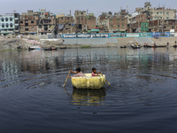 Two boy play with handmade plastic raft in the polluted Buriganga river at Dhaka, Bangladesh on February 06, 2023.  (