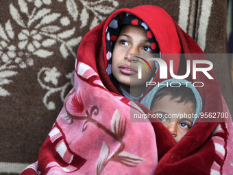 Palestinian siblings warm themselves in front of their home during a stormy weather on February 8, 2023, in Gaza City .
 (