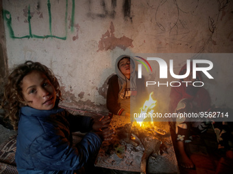 Palestinian children warm themselves by a small fire inside their home during a stormy weather on February 8, 2023, in Gaza City .
 (
