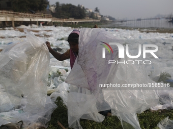 A woman works as she dries polythene plastic bags in Dhaka, Bangladesh on February 9, 2023. (