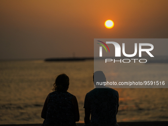 A couple watches the sunset from the Galle Face Promenade in Colombo, Sri Lanka, on February 14, 2023. (