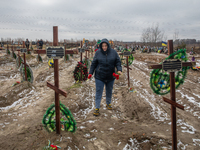 Woman commemorates unidentified peoples who died during the occupation of Bucha and surrounding settlements at the cemetery in Bucha, one ye...