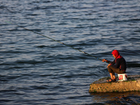 A Palestinian man fish with rods along the beach in Gaza City, on March 1, 2023.  (