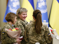 Ukrainian female soldiers stand with flowers and state awards awarded by Ukrainian President to Ukrainian women from the army, rescuers, and...