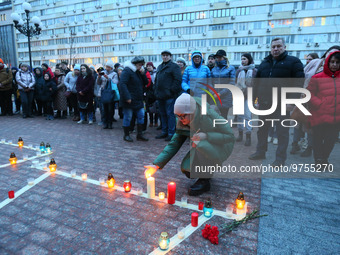 A woman places a candle during a memorial commemorative rally for people killed a year ago inside the Mariupol Drama Theatre building by Rus...
