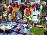 Iranians pose by a tradtional a Haft Sin (Haft Seen) (an arrangement of seven symbolic items that all begin with the letter S in Farsi) duri...