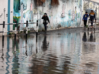 Palestinians walk as a flooded street on a rainy day in Gaza city on March 20, 2023. (
