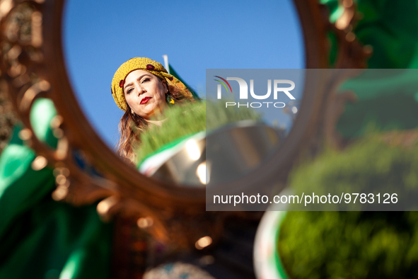 A woman in traditional dress is seen in a mirror on the haft-seen table at a Nowruz celebration on the National Mall. The holiday has its ro...
