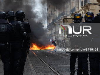 Anti-riot police officers behind a fire set by protesters during a demonstration on a national action day, a week after the government pushe...