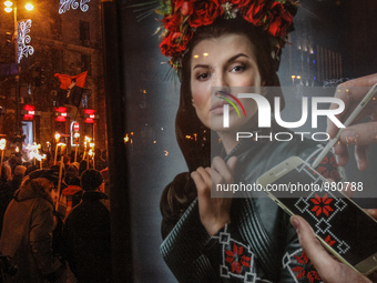 Activists and supporters of Ukrainian nationalists are reflected in advertising as they march with torches and flags in downtown Kiev during...