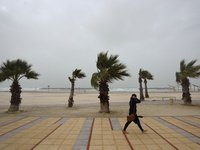 An Israeli woman walks barefoot at the beach on a stormy weather day in the coastal city Herzliya, North of Tel-Aviv on January 08, 2016.  (