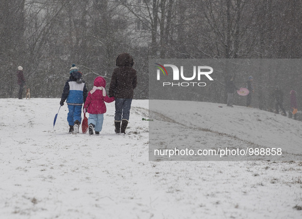 Mother with two children goes sliding down n a small hill next to the house, 08, January, 2016, Warsaw, Poland 