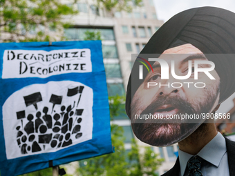 A man wears a mask of incoming World Bank President Ajay Banga during a 