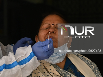 A healthcare worker collects a swab sample of a woman for Covid-19 test, amid a rise in coronavirus cases in the country, in New Delhi on Ap...