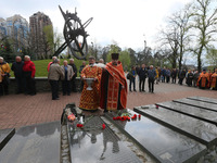 Orthodox priests conduct a service during a commemoration ceremony marking the 37th anniversary of the Chernobyl disaster next to a memorial...