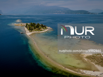 A drone view of people walking towards San Biagio Island, also known as Rabbit Island, on Lake Garda as the lake's water levels recede due t...