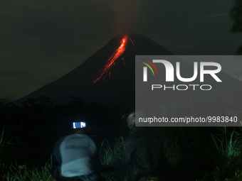 Local villagers take photos as Mount Merapi spews pyroclastic flow as the volcanic activity increases from Tunggularum village, Sleman distr...