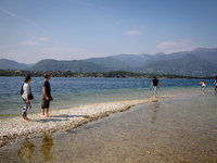People walking towards San Biagio Island, also known as Rabbit Island, on Lake Garda as the lake's water levels recede due to a severe droug...