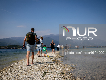 People walking towards San Biagio Island, also known as Rabbit Island, on Lake Garda as the lake's water levels recede due to a severe droug...