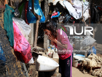 Palestinian Bedouin girl washes her face outside the hut in Gaza City, on May 4, 2014. (