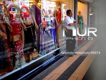 A salesperson waits for customers in front of his store  in Kuala Lumpur, Malaysia, Thursday, May 4, 2014.(