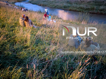 People By River At Sunset