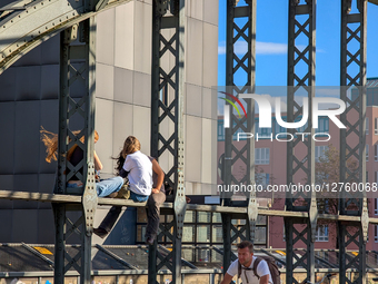 Young People Sitting On Steel Beams On Bridge