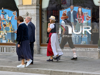 People In Traditional Bavarian Clothing Walking Past Decorated Shop Windows In Munich During Oktoberfest