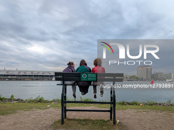 People Sitting On Bench In Autumn By River
