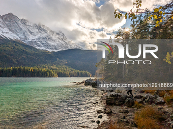 Hikers On Lake Eibsee Shoreline With Snow-Capped Zugspitze Massif