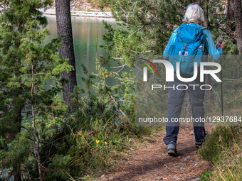 Senior Woman Hikes By Lake Blindsee With Trekking Poles In The Tyrolean Alps