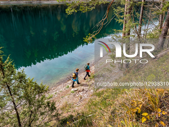 Two Hikers Walk Along The Shore Of Lake Blindsee In The Tyrolean Alps