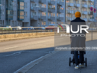 Man Pushing A Baby Stroller Walks Past Apartment Buildings