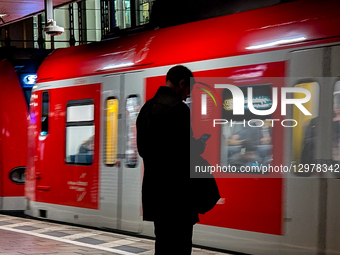 Man Waiting For S-Bahn Using Smartphone On Platform