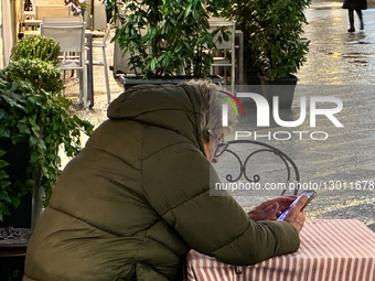 Senior Man Uses Smartphone At Outdoor Cafe In Italy