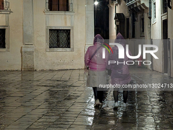 Pedestrians Walk In Pink Rain Ponchos On Wet Pavement At Night