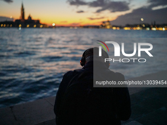Man Listens To Music By The Grand Canal At Dusk