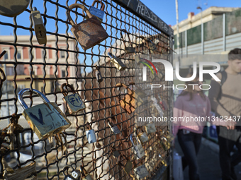 Love Padlocks On Fence As Couple Walks Hand In Hand
