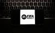 A laptop keyboard and FIFA Mobile logo displayed on a phone screen are seen in this illust...
